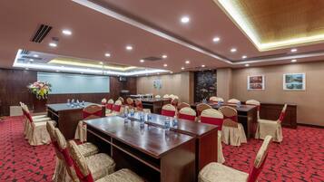 A conference room with a long table, chairs, and a projector screen.