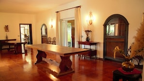 A dining area with a wooden table and chairs, a vase with dried flowers, and a mirror on the wall.