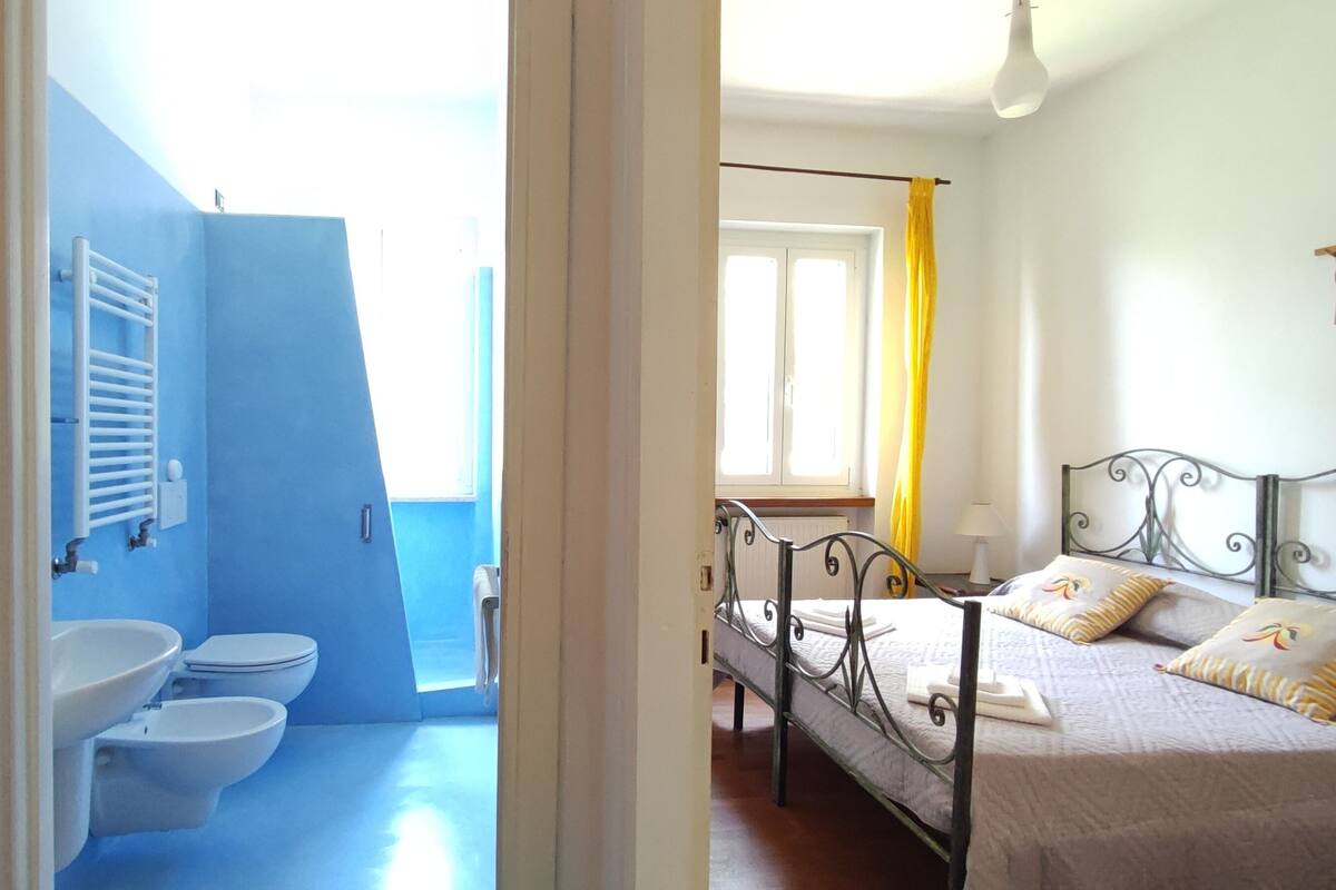 A bathroom with a blue wall, a white sink, and two toilets.