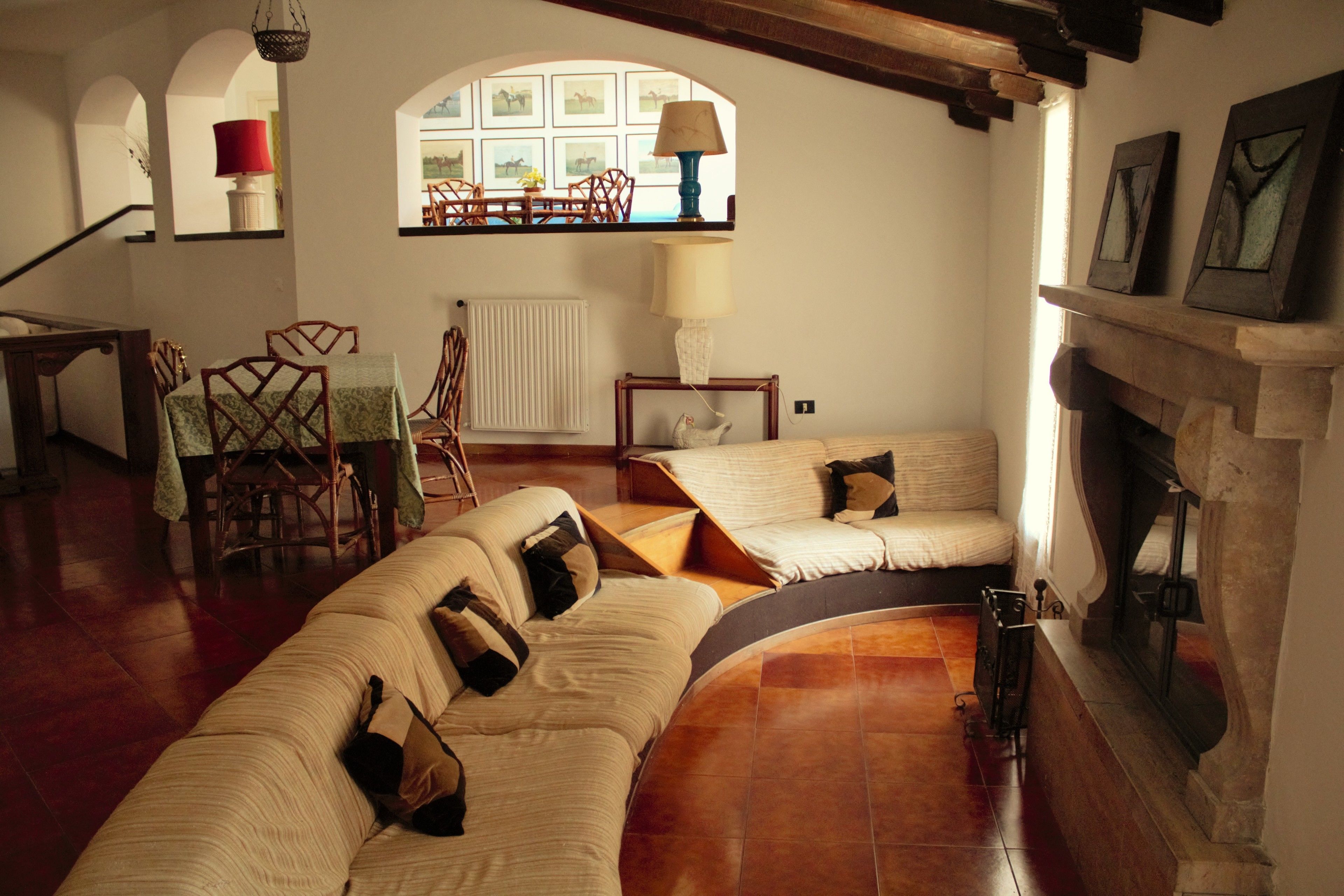 Una sala de estar acogedora con un sofá curvo, una chimenea y un comedor con sillas y una mesa.