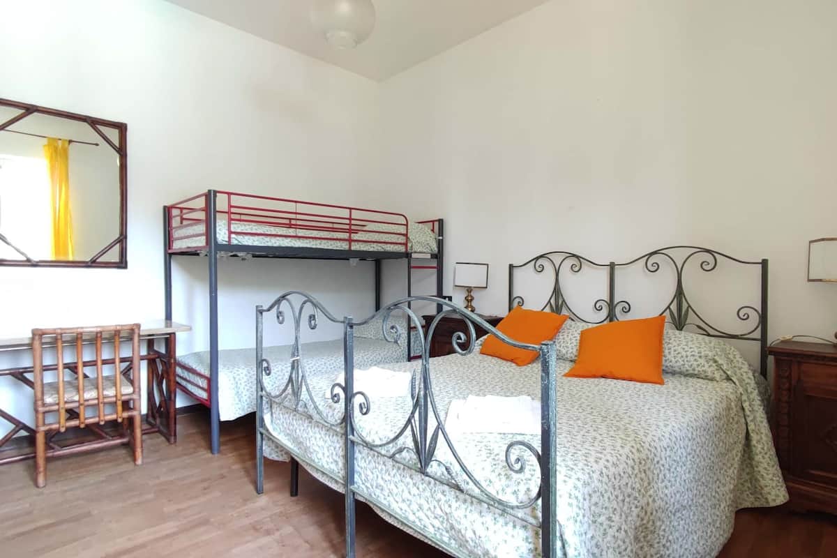 A dorm-style room with bunk beds, a desk, and a chair.