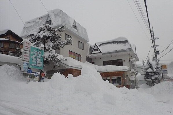 A building with a snow-covered roof and a signboard in front.