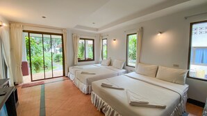 A hotel room with two beds, a sliding glass door leading to a garden, and a small desk with a chair. - Samui Honey Backpacker Bungalow (Koh Samui)