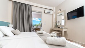 Una habitación de hotel con cama, escritorio, silla, televisión y aire acondicionado.