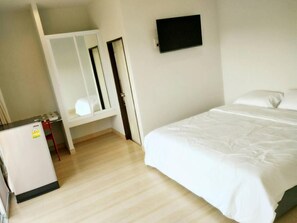 A bedroom with a bed, a small desk, a mirror, and a TV mounted on the wall. - R.M. Mansion Surin (Surin)