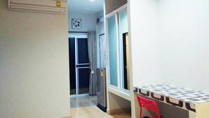 A narrow hallway with a window, a door, and a small table with a chair. - R.M. Mansion Surin (Surin)