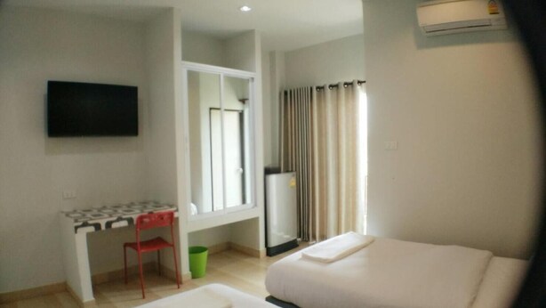 A hotel room with two beds, a desk, a chair, a TV, and an air conditioning unit. - R.M. Mansion Surin (Surin)