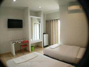 A hotel room with two beds, a desk, a chair, a TV, and an air conditioning unit. - R.M. Mansion Surin (Surin)