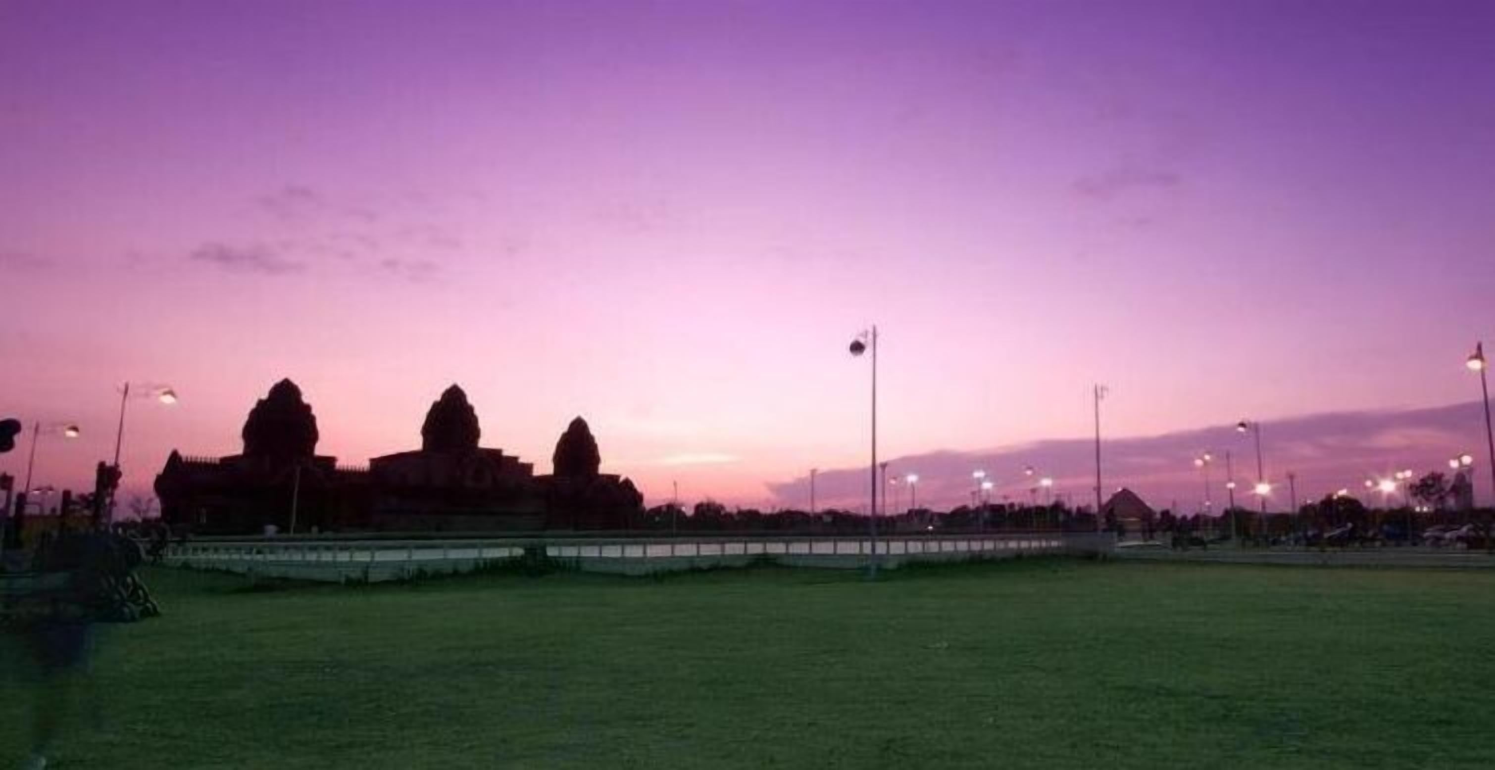 A stadium with a large field and a few buildings in the background.