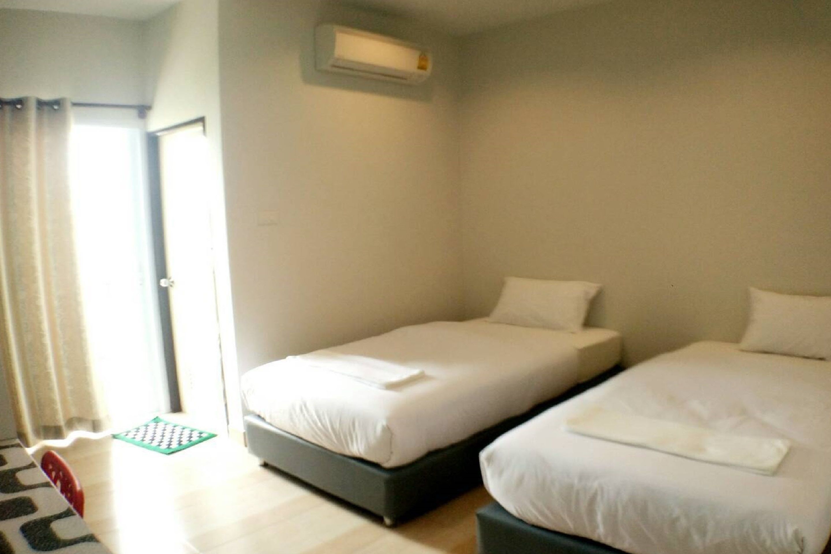 A hotel room with two beds, a small table, and a window with curtains.