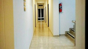 A long, narrow hallway with a light-colored floor, a fire extinguisher mounted on the wall, and a staircase on the right. - R.M. Mansion Surin (Surin)