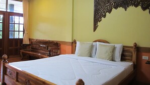 A bedroom with a large bed, wooden headboard, and a decorative wall hanging. - Phuendernthang Resort (Tha Chang)