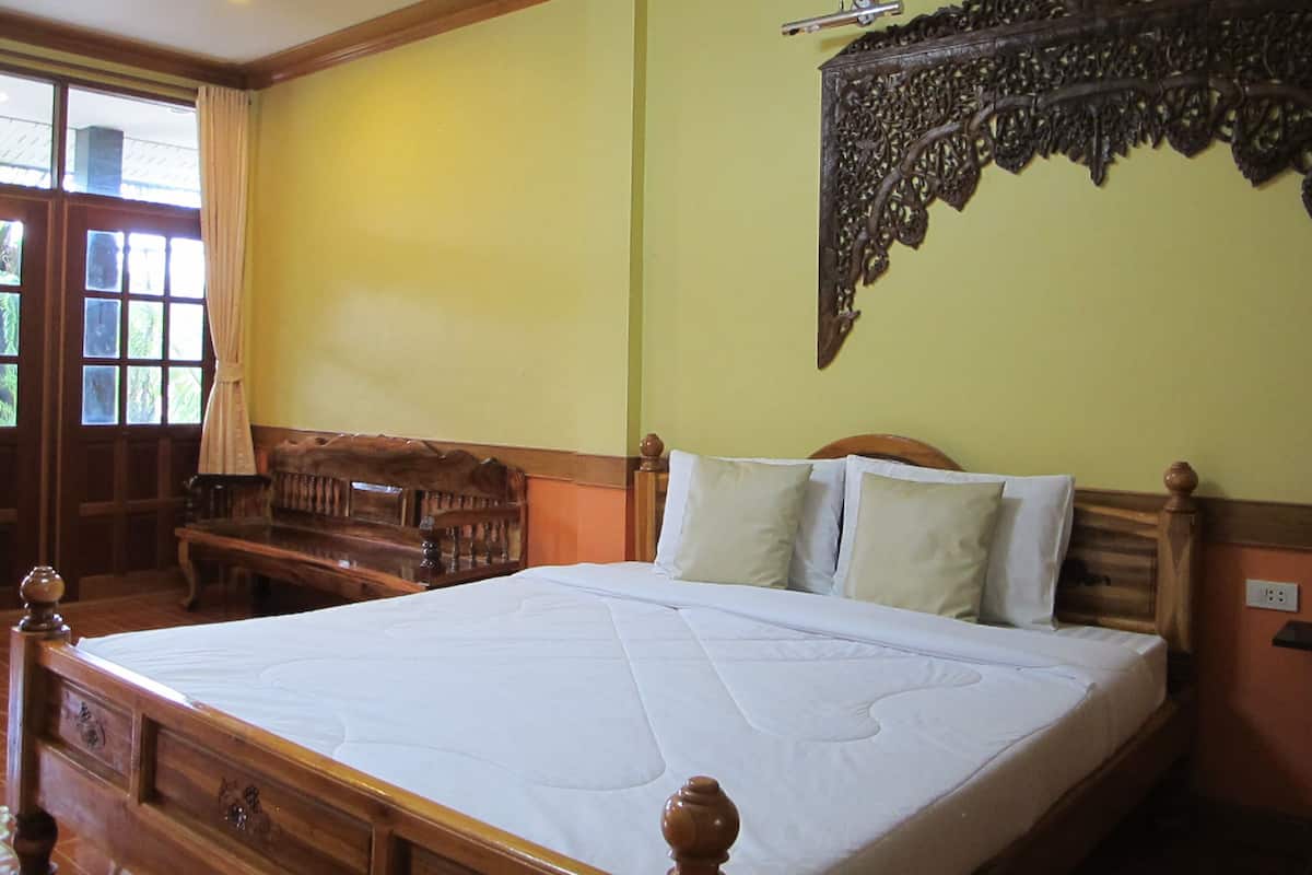 A bedroom with a large bed, wooden headboard, and a decorative wall hanging.