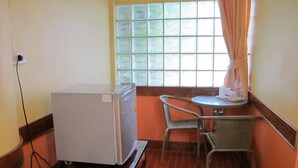 A compact kitchen with a refrigerator, a small dining table, and a chair. - Phuendernthang Resort (Tha Chang)