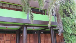 A building with a green and brown facade, wooden doors, and hanging palm fronds. - Phuendernthang Resort (Tha Chang)