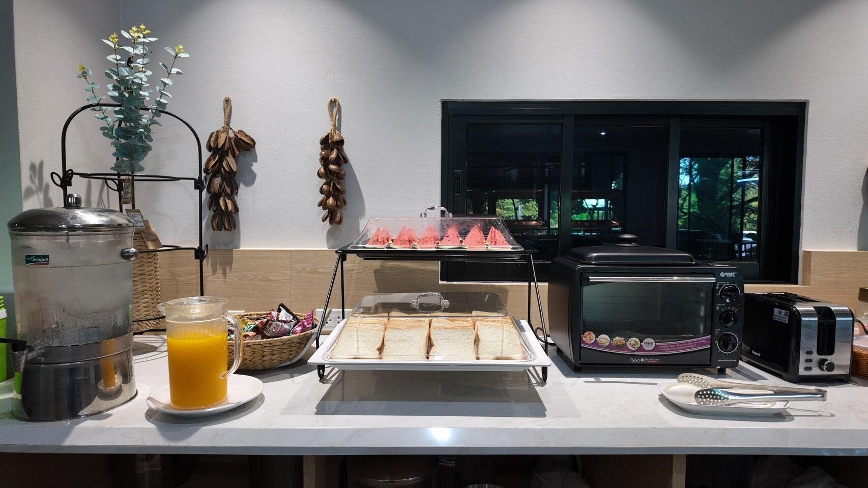Ein Frühstücksbuffet mit Kaffeemaschine, Toaster und einem Glas Orangensaft.