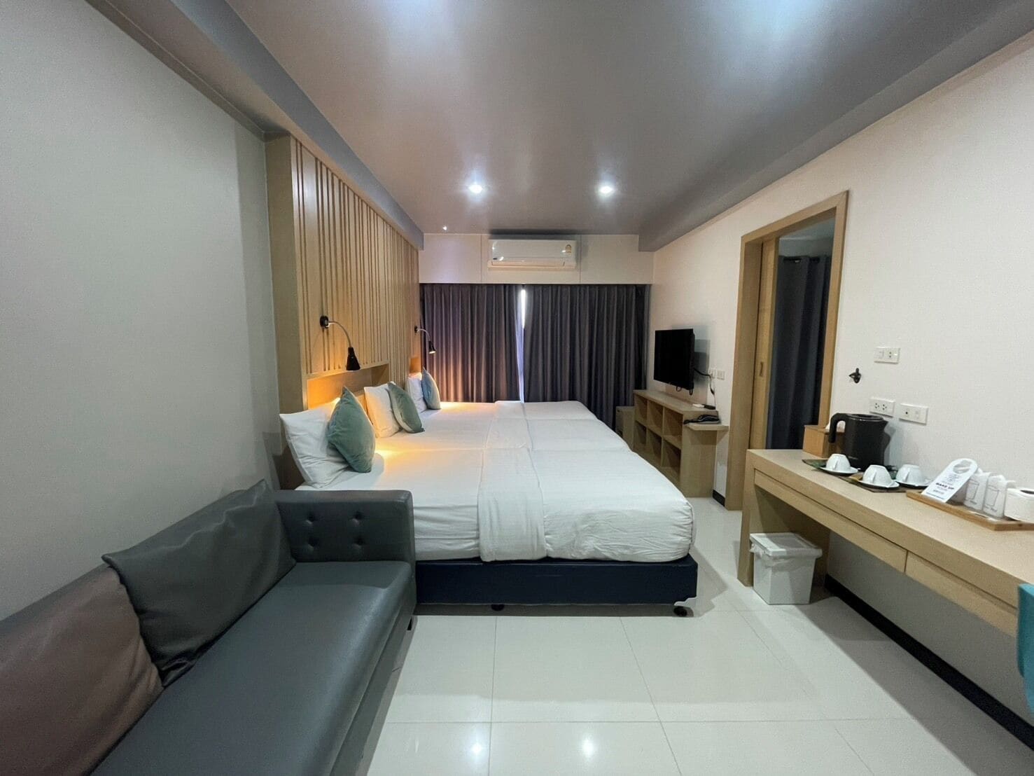 Une chambre d’hôtel moderne équipée d’un lit, d’un canapé, d’un bureau avec une télévision et d’un miroir.