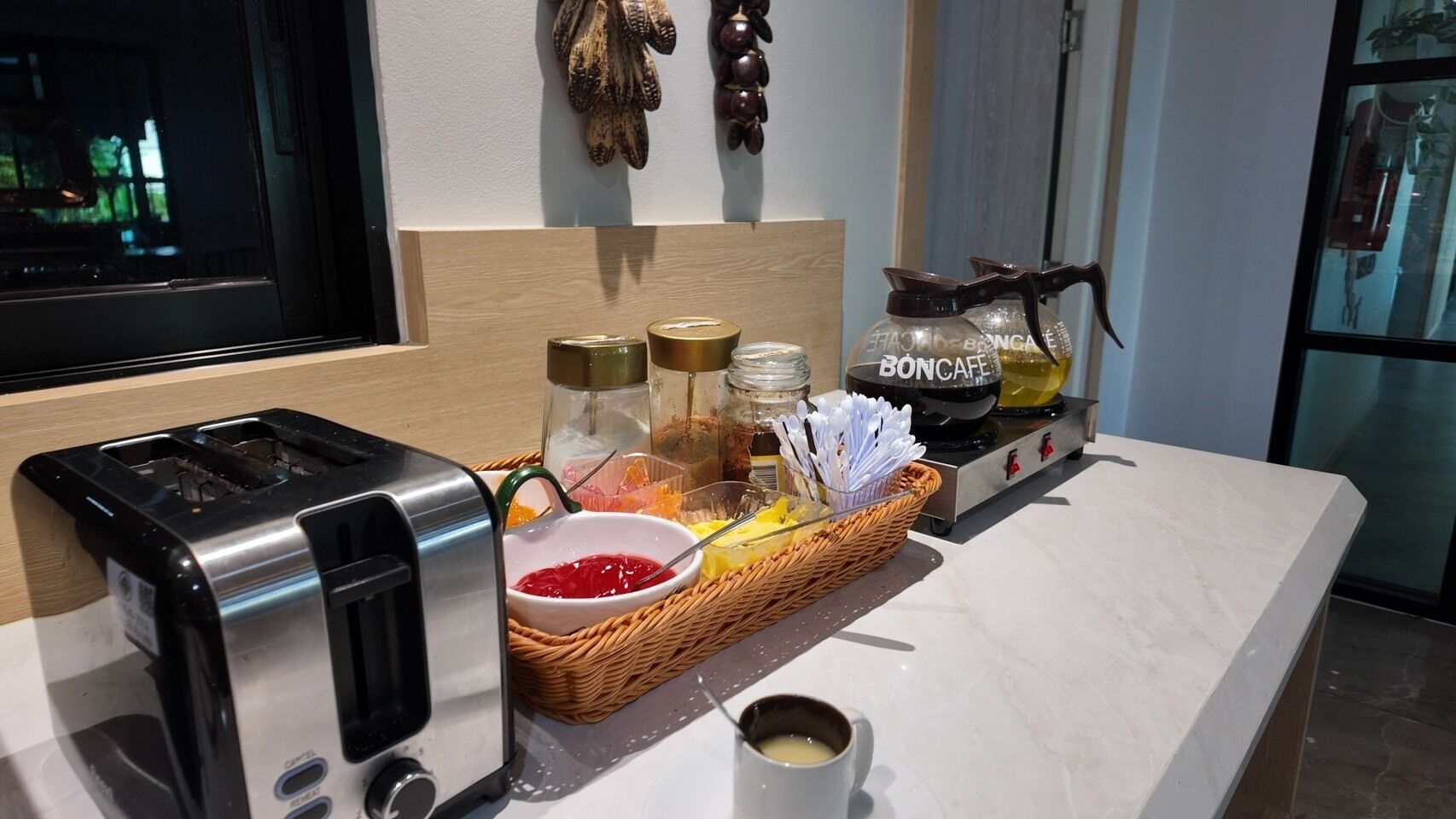 A kitchen counter with a toaster, a basket of breakfast items, and a coffee maker.