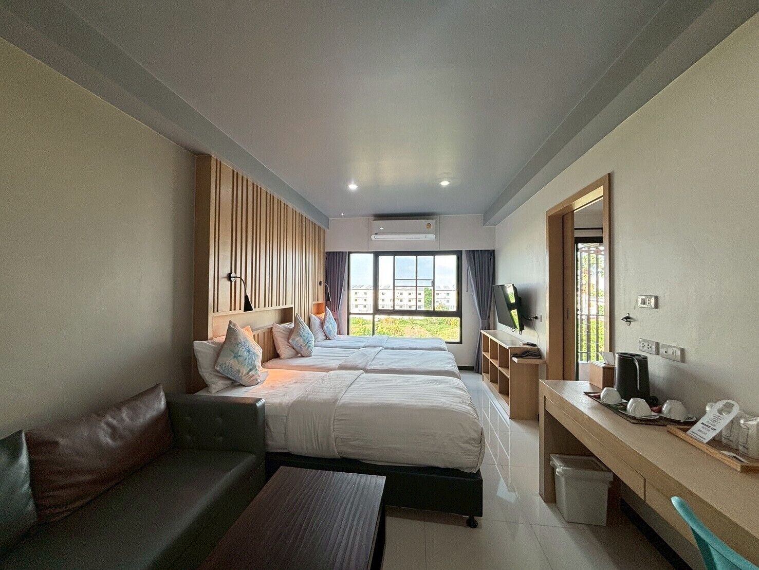 Una habitación de hotel con dos camas, un sofá, un escritorio y un televisor.