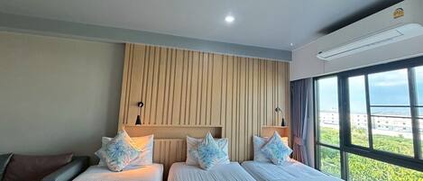 Habitación de hotel con dos camas, un panel de pared de madera, un ventanal con vistas y un equipo de aire acondicionado.