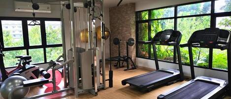 Un gimnasio con equipo cardiovascular, máquinas de pesas y vistas a zonas verdes a través de amplios ventanales.
