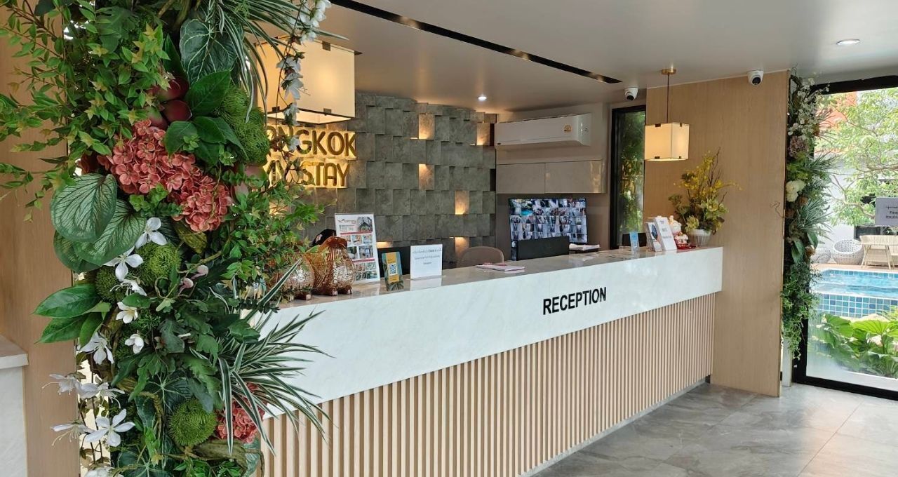 A reception area with a modern design, featuring a reception desk, a stone wall, and a view of a pool.