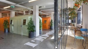 A modern indoor space with a central seating area, potted plants, and a visible exit sign.