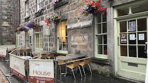 A stone building with a sign reading "The Coffee House" and outdoor seating with wicker chairs. - The Coffee House Hotel (Aberdeen)