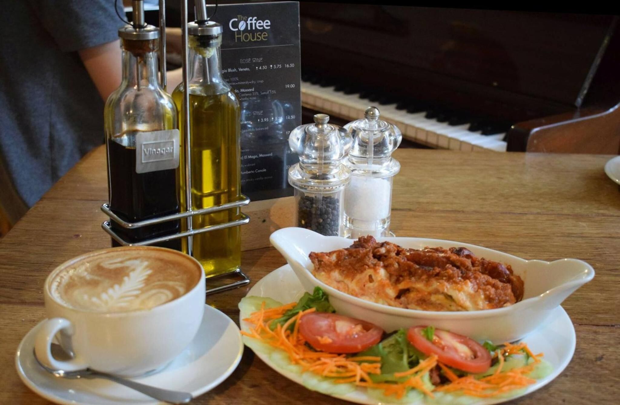 Une table avec une tasse de café, une assiette de salade et deux bouteilles de vin.