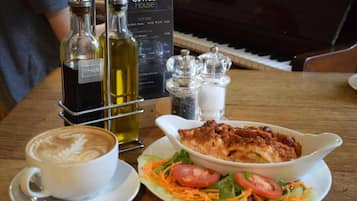 Une table avec une tasse de café, une assiette de salade et deux bouteilles de vin.