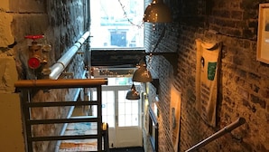 A narrow stairway with a metal handrail, a wooden banister, and a view of the outside through a window. - The Coffee House Hotel (Aberdeen)