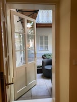 Abertura de porta para um pátio exterior com uma cadeira de vime e uma janela com um letreiro.