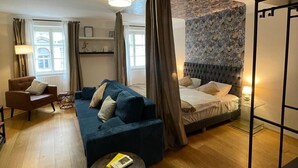 A modern bedroom with a bed, a sofa, a chair, and a small table. - KH Apartments (Vienna)