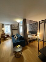 A modern bedroom with a bed, a sofa, a chair, and a small table.