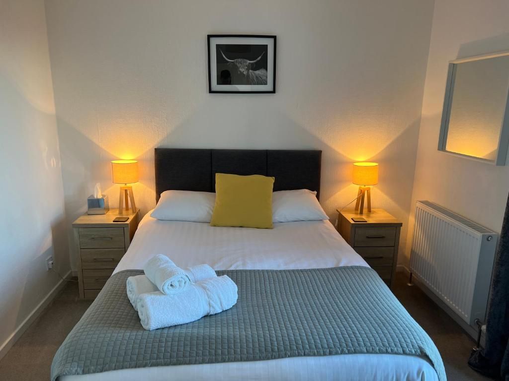 A hotel room with a bed, two bedside tables, a nightstand, a radiator, and a framed picture on the wall.