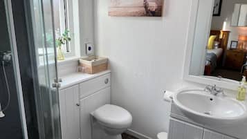 A bathroom with a shower, toilet, sink, and a mirror.