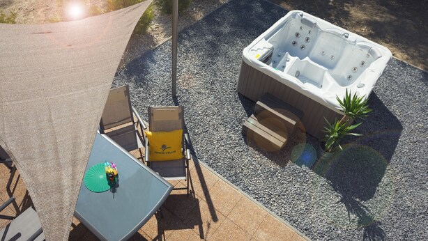 Un bain à remous avec un espace salon, une table et une chaise dotée d’un parasol.