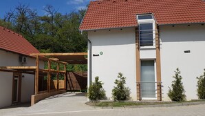 Un bâtiment avec un toit recouvert de tuiles rouges, une structure en bois abritée et un petit escalier menant à une porte.