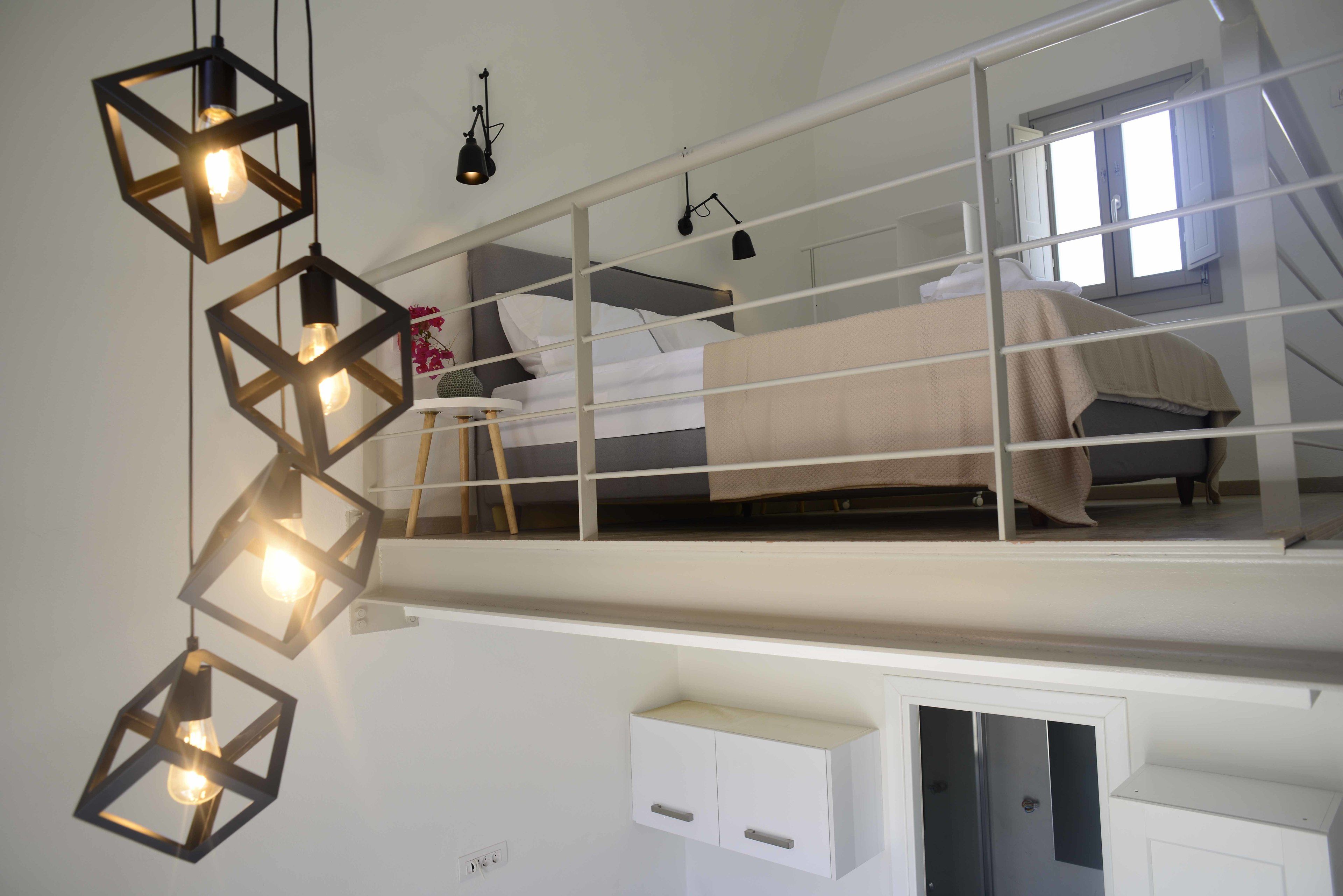 Een slaapkamer met een stapelbed, een witte garderobe en geometrische hanglampen.