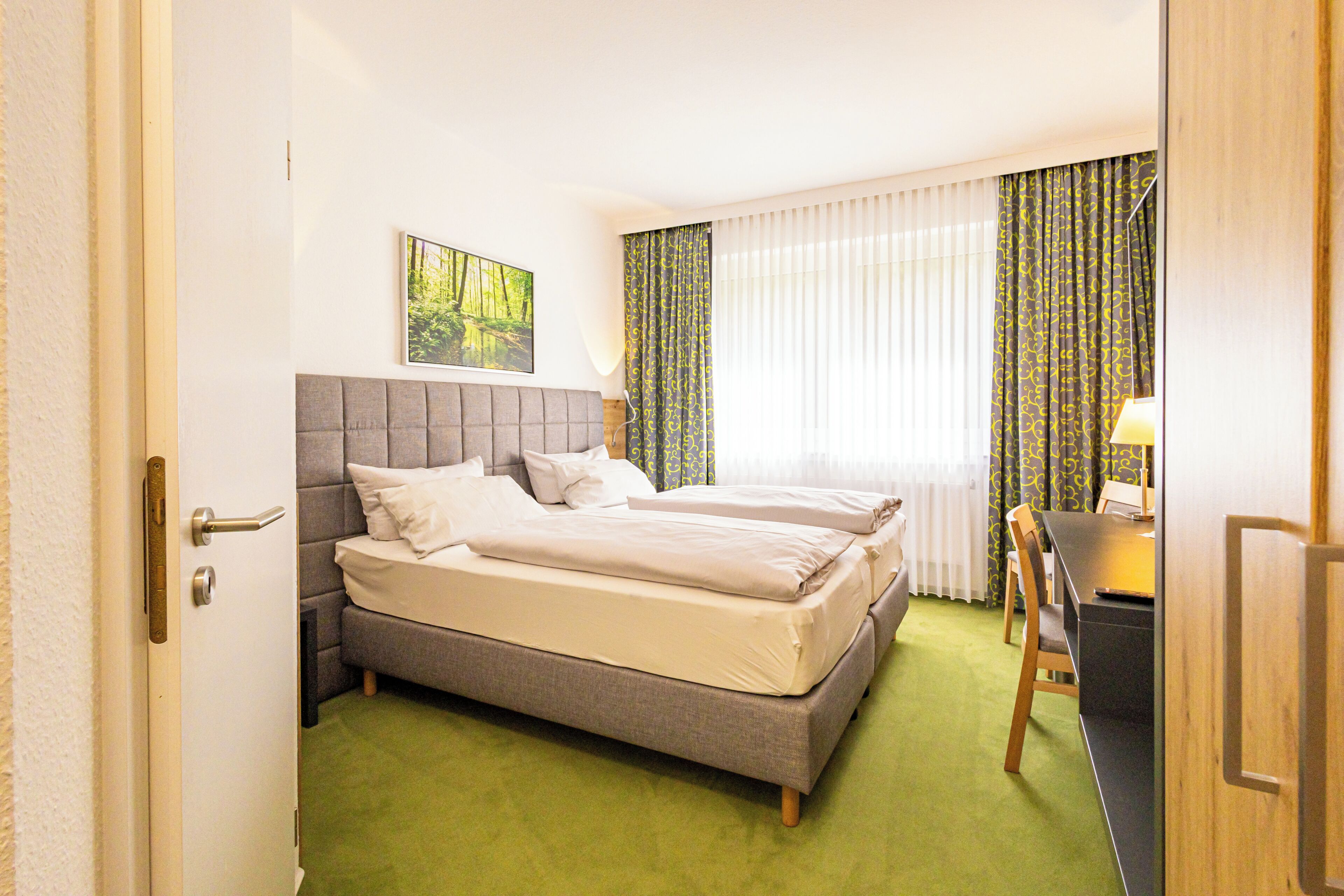 Et hotelværelse med en dobbeltseng, et skrivebord og en stol.