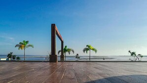 Een open houten terras met palmbomen en een helder uitzicht op de oceaan.