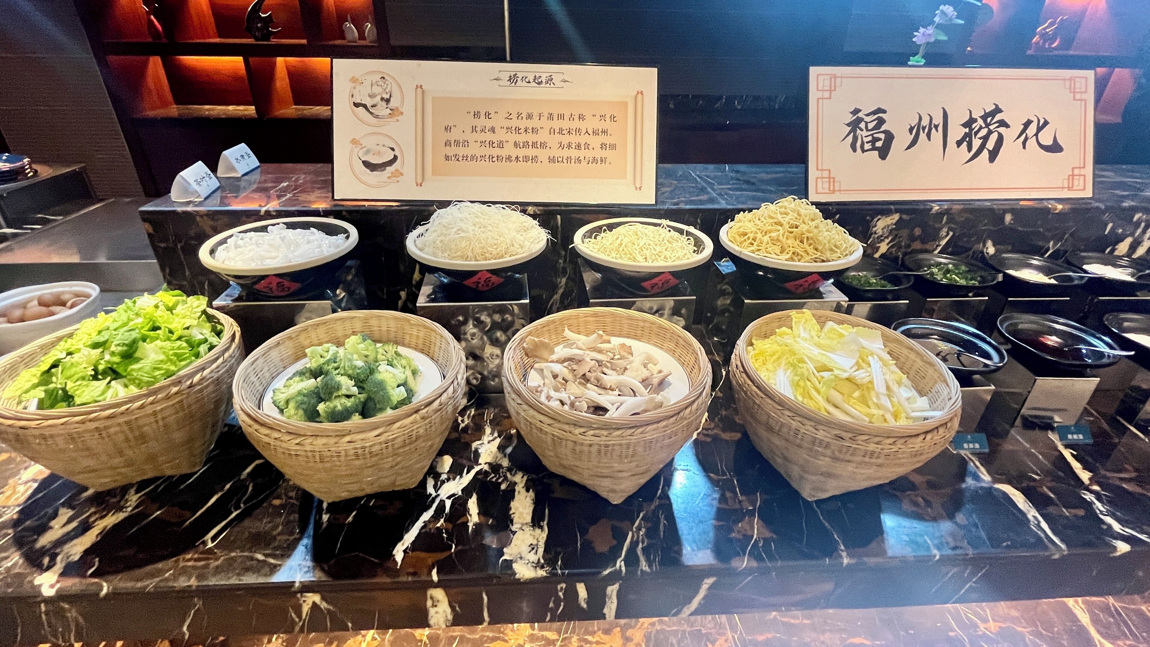 A buffet with various food items including vegetables and noodles.