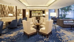 A hotel lobby with a central seating area, a bar, and a view of palm trees through large windows. - Yiho Hotel Bamin Fuzhou (Fuzhou)