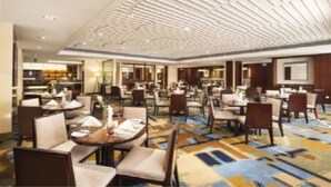 A hotel dining area with multiple tables and chairs, a patterned carpet, and a ceiling with a unique design. - Yiho Hotel Bamin Fuzhou (Fuzhou)