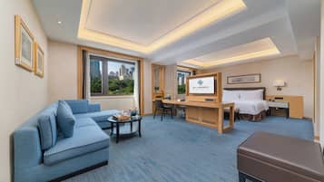 Een hotelkamer met een bank, een bureau met een computer, een bed en een televisie.