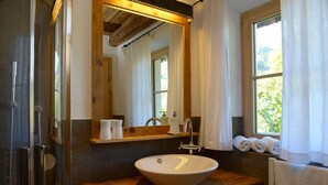 A bathroom with a wooden vanity, a large mirror, a sink, and a window with curtains.