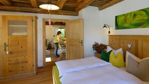 A wooden-floored bedroom with a bed, pillows, and a painting.
