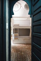 Una cama litera con colchón blanco y una litera inferior con estructura de madera.