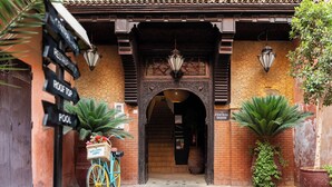 Une entrée d’immeuble de style traditionnel, avec un panneau indicateur indiquant la direction de la piscine, du toit-terrasse et du bâtiment principal.