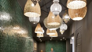 Un área de recepción con mostrador, varias sillas y lámparas de mimbre colgantes.